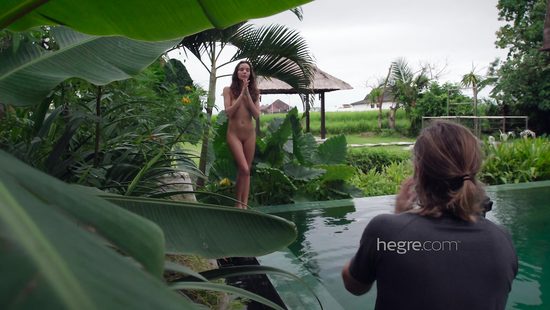 Stunning girl poses near a pool for a cameraman